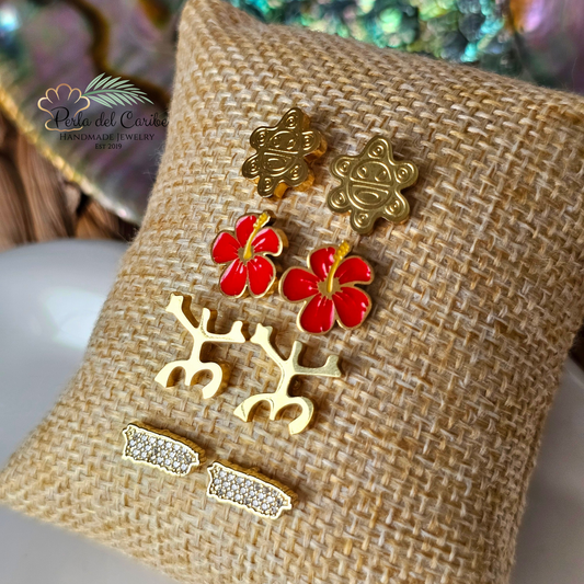 Jewelry set with gold and red earrings on a textured beige surface.